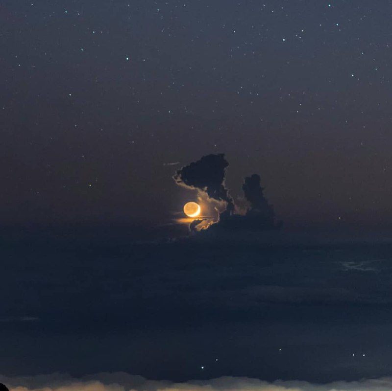 عکس دیدنی حلال ماه در پشت ابر کومولوس، که از ۱۰، ۰۰۰ فوت بالایی از آتشفشان هاوایی قرار گرفته. _. 🆔